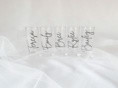 four shot glasses with the words bride and groom written in cursive writing on them