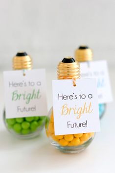 two small glass jars filled with yellow and green candies, one has a sign that says here's to a bright future