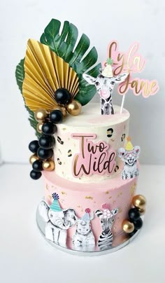 a three tiered cake decorated with animals and palm fronds is on display