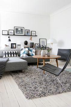 a living room filled with furniture and pictures on the wall above it is an area rug that has been placed in front of a gray couch