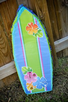 a surfboard is propped up against a fence with flowers and leaves on the board