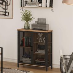 a room with a book shelf and some pictures on the wall above it, along with a plant