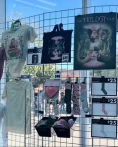 there are many t - shirts on display in the store window, including ones with tattoos