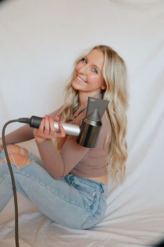 a woman sitting on the floor holding a hair dryer