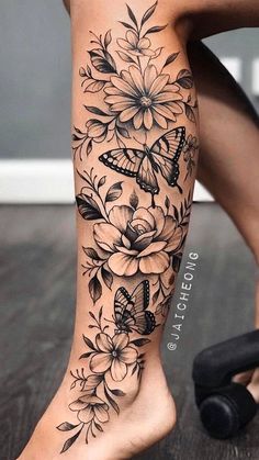 a woman's leg with flowers and butterflies on it, while she has her legs tattooed