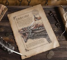 an old book with a dragon on it next to some coins and a feather quill