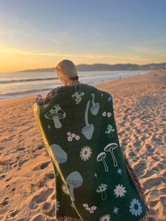 a woman wrapped up in a blanket on the beach