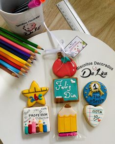 decorated cookies and pencils are on a table with markers, books, and other school supplies