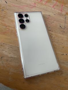 the back of an iphone 11 pro on a wooden surface with three black and white buttons