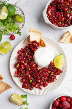 a white plate topped with cranberry salsa next to two bowls filled with fruit