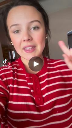 a woman in a red and white striped shirt is holding her cell phone up to the camera