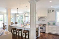 a large kitchen with white cabinets and wooden flooring, along with an island in the middle