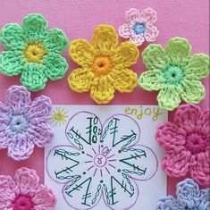 colorful crocheted flowers are displayed on a pink background with a sign that says joy