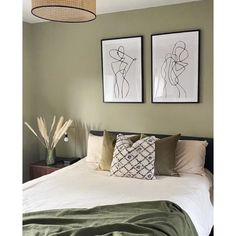 two framed pictures hang on the wall above a bed with white sheets and green pillows