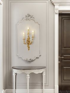 a white table sitting in front of a mirror with candles on the wall behind it