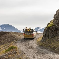 a car driving down a dirt road with a bike on the back