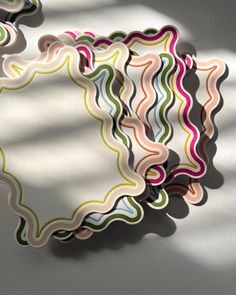 an abstract paper plate with wavy lines on the surface and shadows cast on the wall