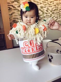 a baby in a cup costume sitting on a table