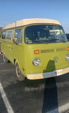 an old vw bus is parked in a parking lot with other cars behind it