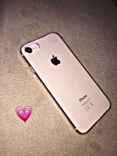 an iphone is laying on the ground with a pink heart sticker next to it