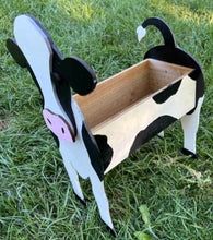 a cow shaped bench sitting in the grass