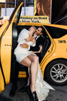 a newly married couple kissing in the back of a taxi cab on their wedding day