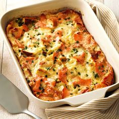 a casserole with tomatoes and cheese in a white dish next to a fork