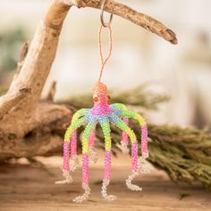 an ornament hanging from a tree branch on a piece of wood with branches in the background