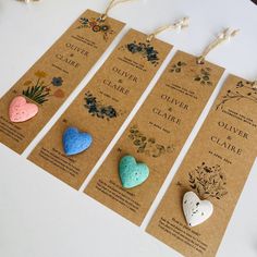 four tags with hearts on them are hanging from twine strings and decorated with flowers