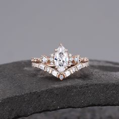 an engagement ring with two rows of diamonds set on top of a stone slab in front of a gray background