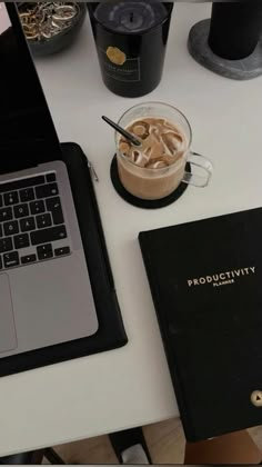 a laptop computer sitting on top of a desk next to a cup of coffee and a notebook