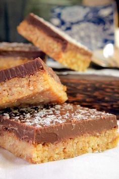 three pieces of chocolate and peanut butter bars stacked on top of each other in front of a plate