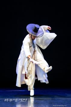 a man in white is dancing on stage with a hat and coat over his head