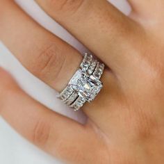 a woman's hand with a diamond ring on top of her finger and an engagement band