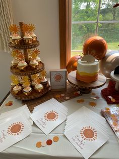 a table topped with cupcakes covered in frosting next to a cake on top of a wooden stand