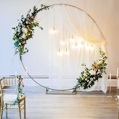 a wedding arch decorated with flowers and greenery in front of the ceremony room set up