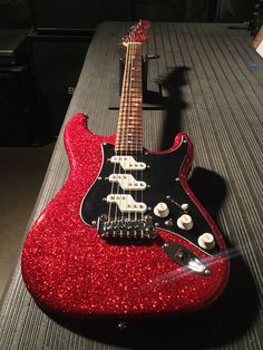 a red electric guitar sitting on top of a table