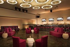 a room filled with lots of red couches and chairs next to a tall bar