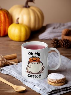 a white coffee mug with a cartoon cat on it next to some cinnamon sticks and pumpkins