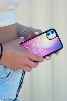 a person holding a cell phone in their left hand and wearing a white shirt with the word love on it