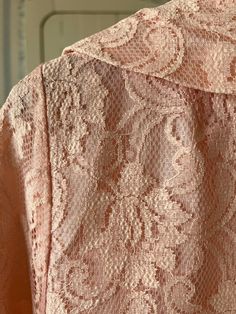 This lovely long jacket is made from gorgeous pink floral lace over a lightweight layer of matching pink satiny fabric. It has a wide collar and an open front with no buttons or snaps. The measurements, taken with the coat lying flat, are: shoulder to shoulder, 14 inches; armpit to armpit, 22 inches; sleeves, 17 inches; length, 37 inches; bottom edge, 26 inches. In very good condition. Elegant Pink Lace For Summer, Pink Spring Lace Dress With Delicate Details, Pink Lace Dress With Lace Patchwork For Spring, Spring Pink Delicate Lace Dress, Pink Delicate Lace Dress For Spring, Feminine Long Sleeve Lace Dress, Formal Pink Long Sleeve Lace Dress, Pink Elegant Lace Dress, Pink Long Sleeve Lace Dress With Lace Patchwork