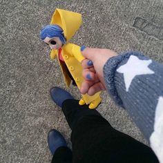 a person holding a yellow toy with a blue hat and star on it's head