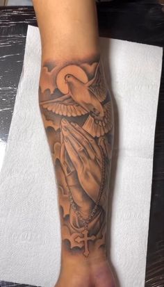 a person with a tattoo on their arm and foot is holding a dove in the sky