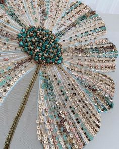 a close up of a decorative object made out of beads and sequins on a white surface