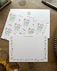 two cards with pink flowers on them next to some glasses