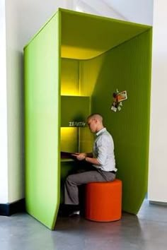 a man sitting on a stool in a room with green walls and an orange ottoman