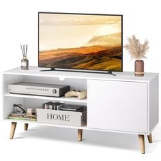 a flat screen tv sitting on top of a white entertainment center next to a plant