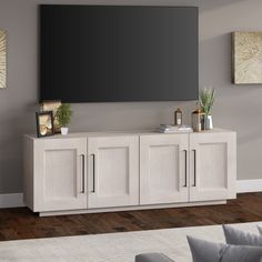 a large flat screen tv mounted to the side of a white cabinet in a living room