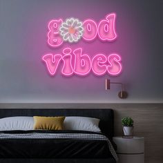 a neon sign that reads boo's vibes on the wall above a bed