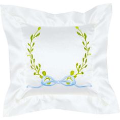 a white pillow with an embroidered wreath on the front and blue ribbon at the back